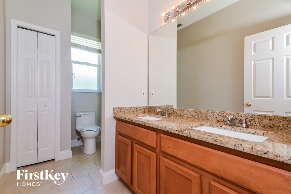 A bathroom with a granite countertop and a toilet in the background.