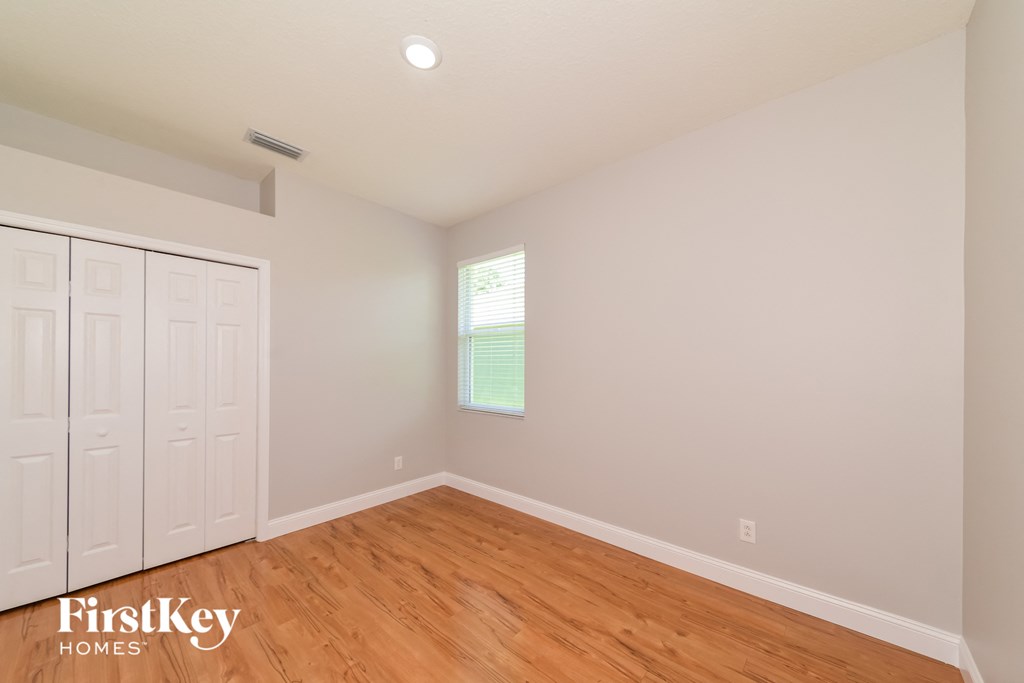 A room with wooden floors and white walls, with a window on the wall.