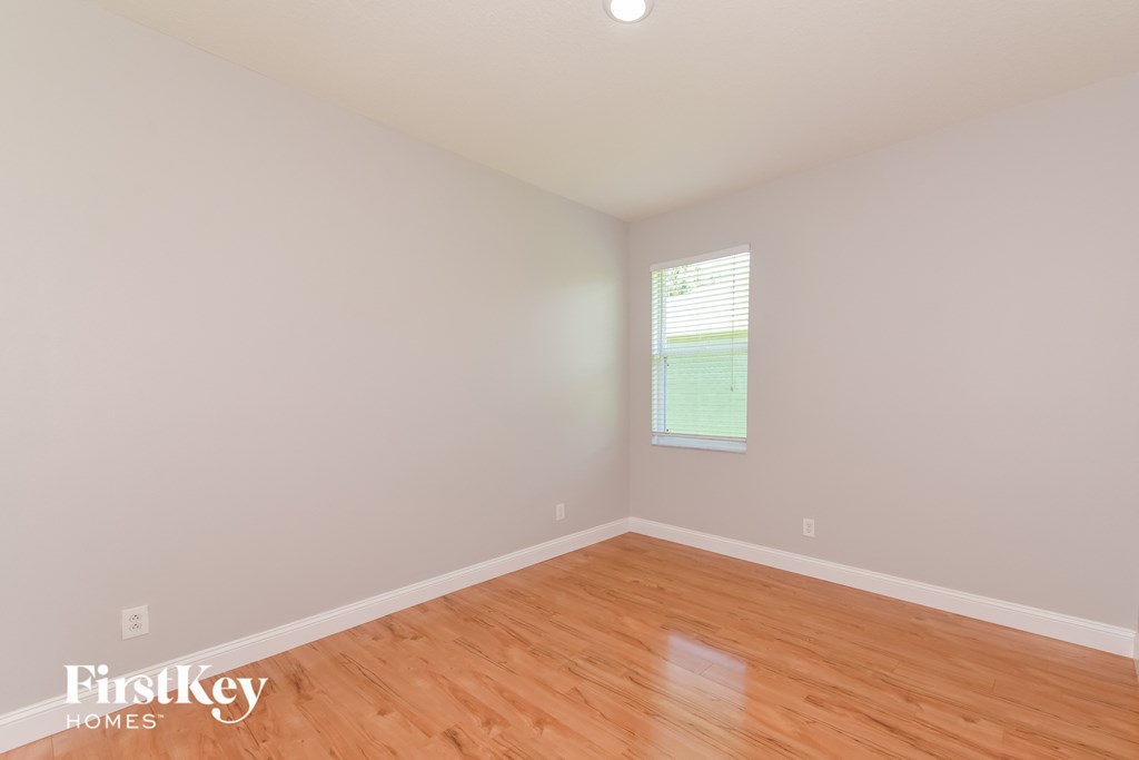 A room with wooden flooring and a window with blinds.
