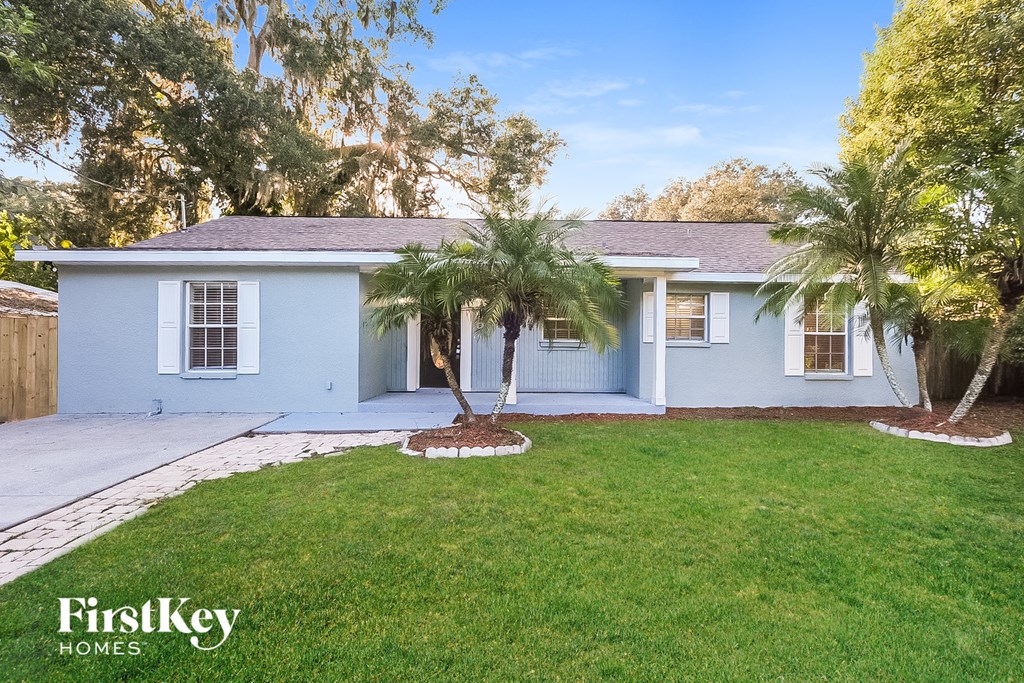 a blue house with a lawn and palm trees