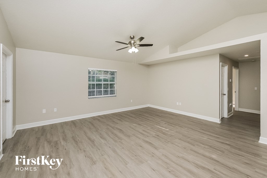 the spacious living room with hardwood floors and a ceiling fan