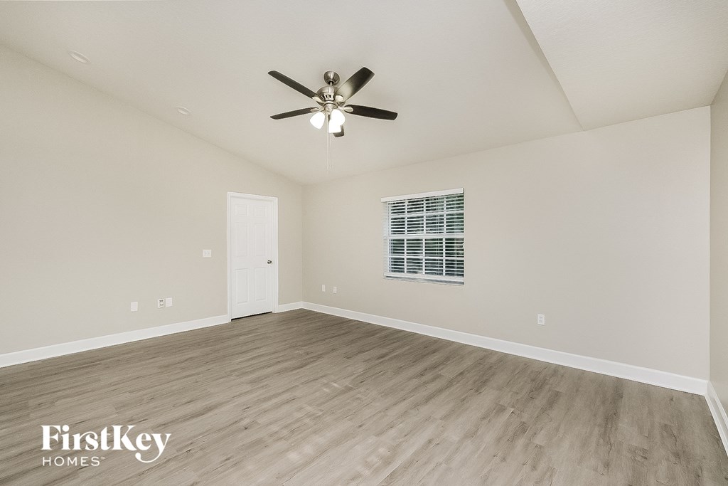 the spacious living room with hardwood floors and a ceiling fan