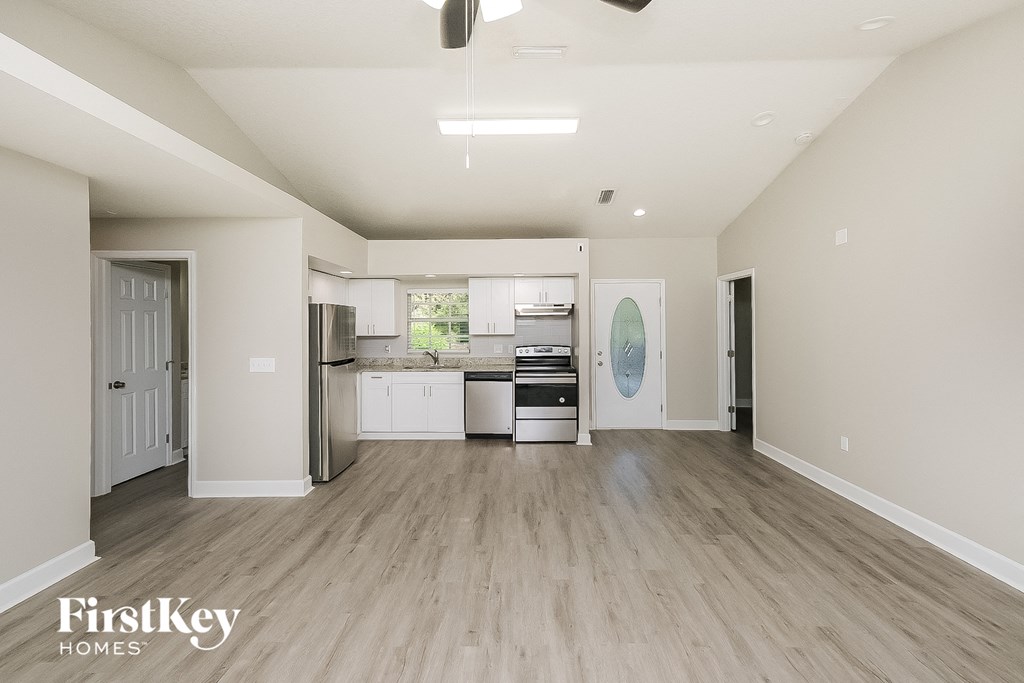 a kitchen and living room with a hardwood floor and white walls