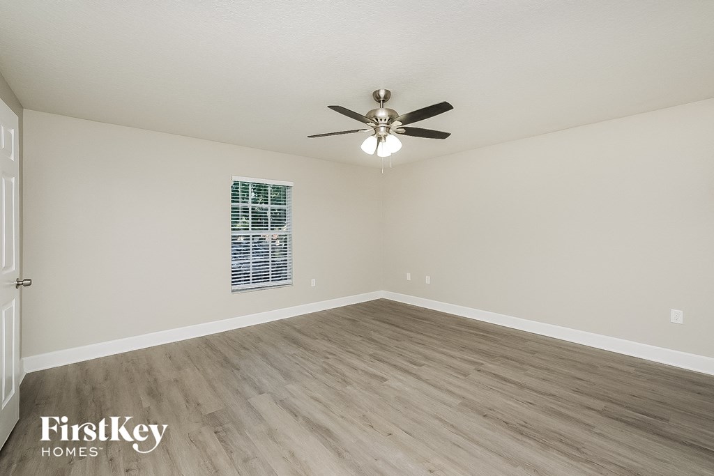 a spacious living room with hardwood floors and a ceiling fan