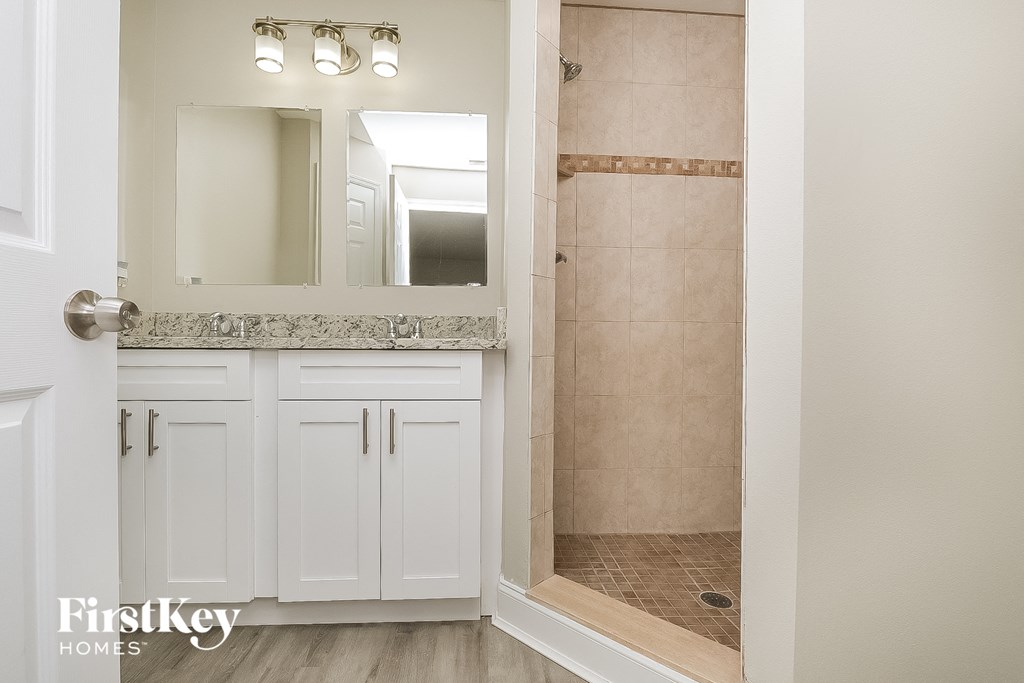 a bathroom with white cabinets and a shower and a sink
