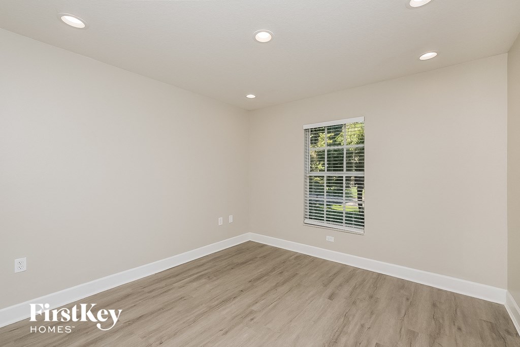 the spacious living room with hardwood flooring and a window