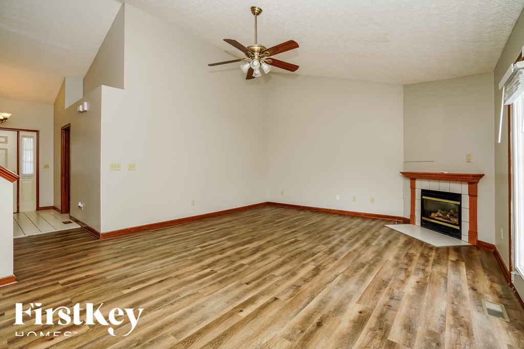 A spacious room with a fireplace and a ceiling fan.