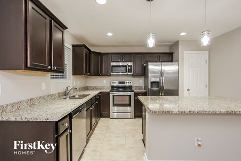A kitchen with dark brown cabinets and a granite countertop.