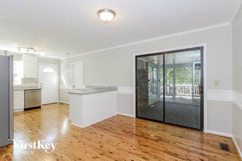 A spacious room with wooden floors and a kitchen area in the background.
