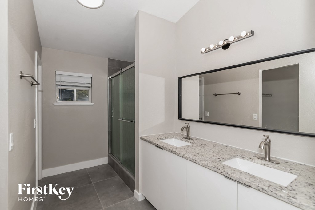 a bathroom with two sinks and a mirror and a shower