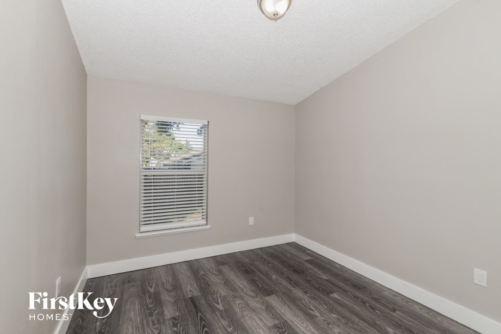 the living room of an apartment with wood flooring and a window
