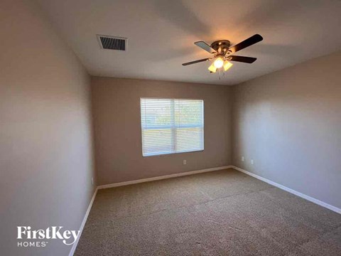 A room with a ceiling fan and a window with blinds.