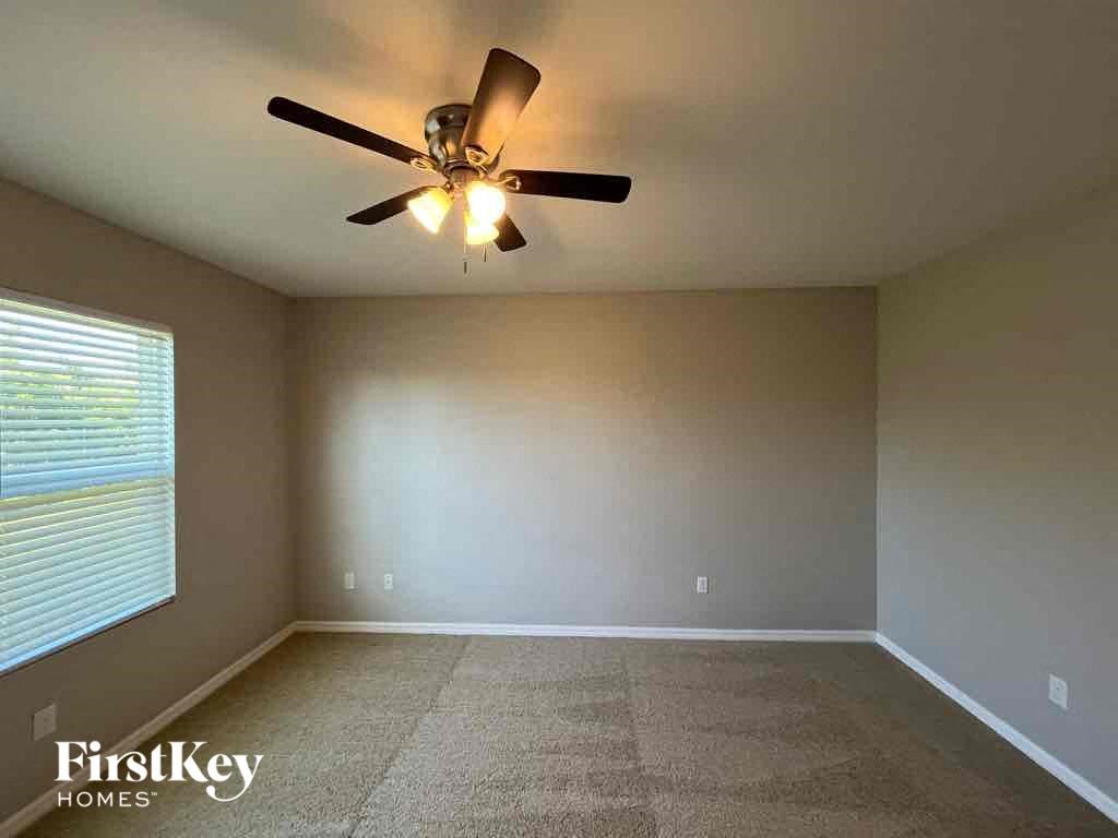 A room with a ceiling fan and carpeted floor.