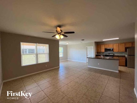 A spacious living room with a kitchen in the background.
