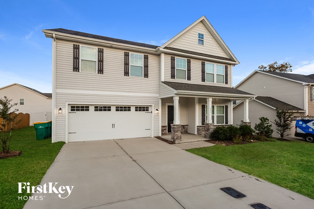 a beige house with a white garage door and a driveway