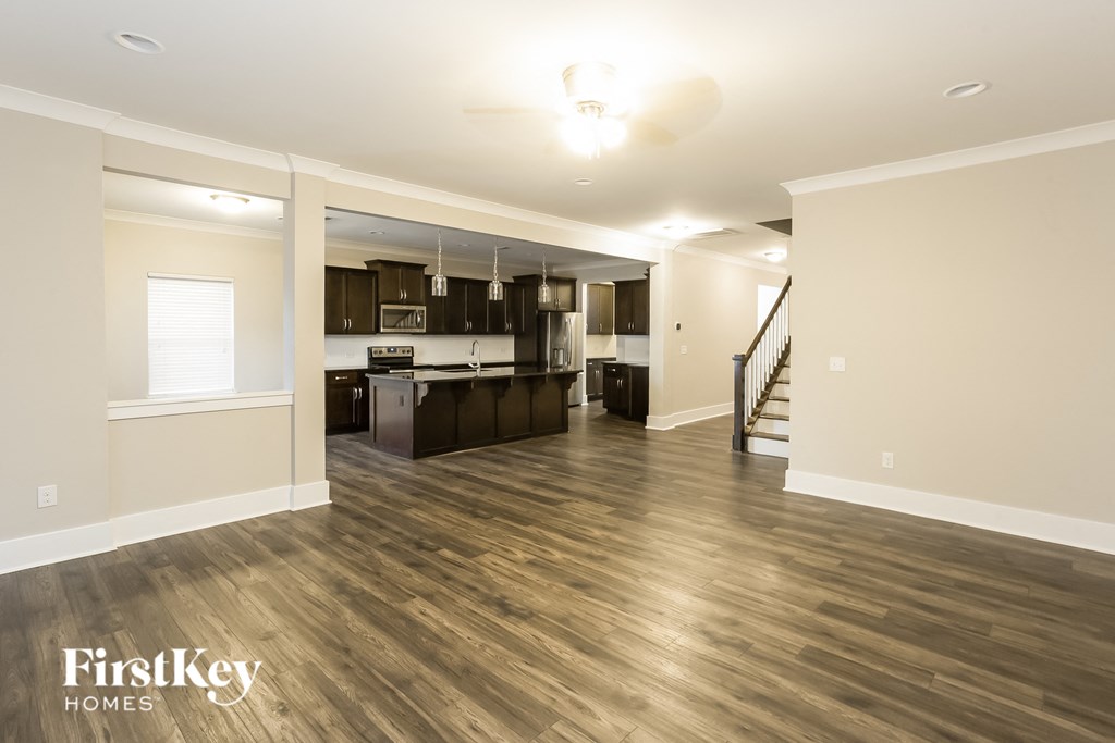 an empty living room and kitchen with wood flooring
