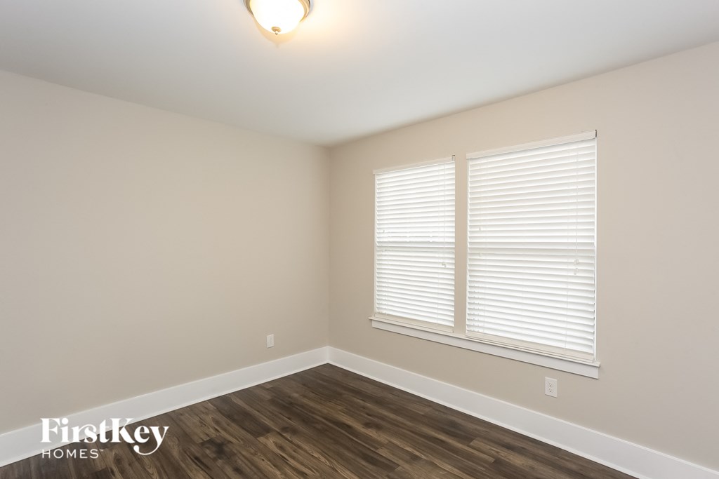 the upstairs bedroom with wood flooring and two windows