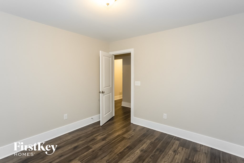 the living room of an apartment with wood floors and white walls