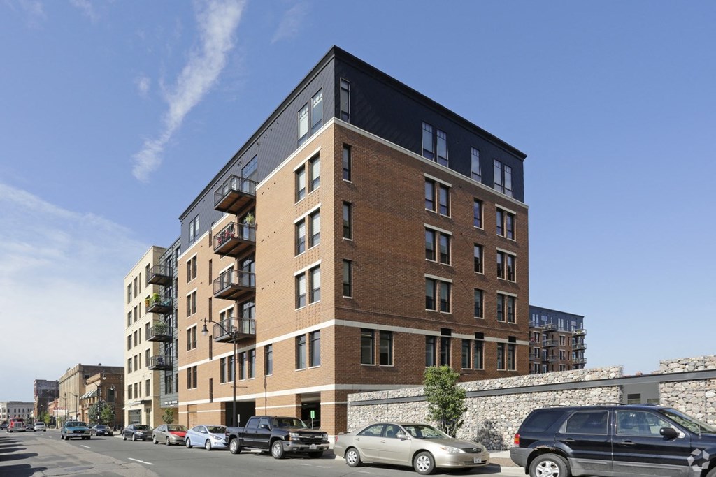 a tall brick building with cars parked on a city street