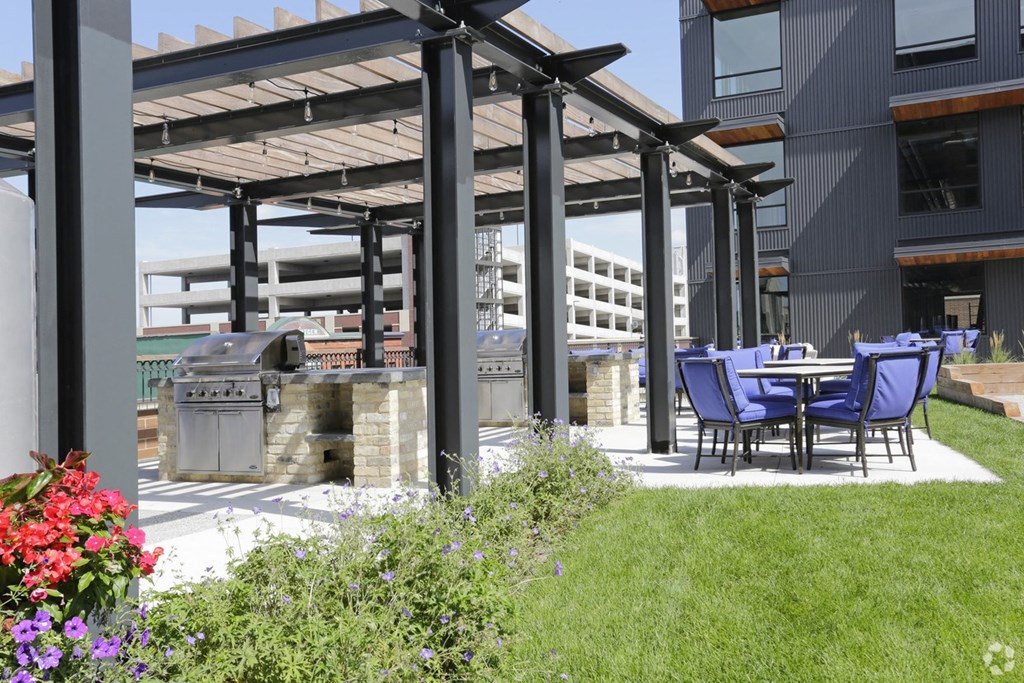 a patio with tables and chairs and a grill