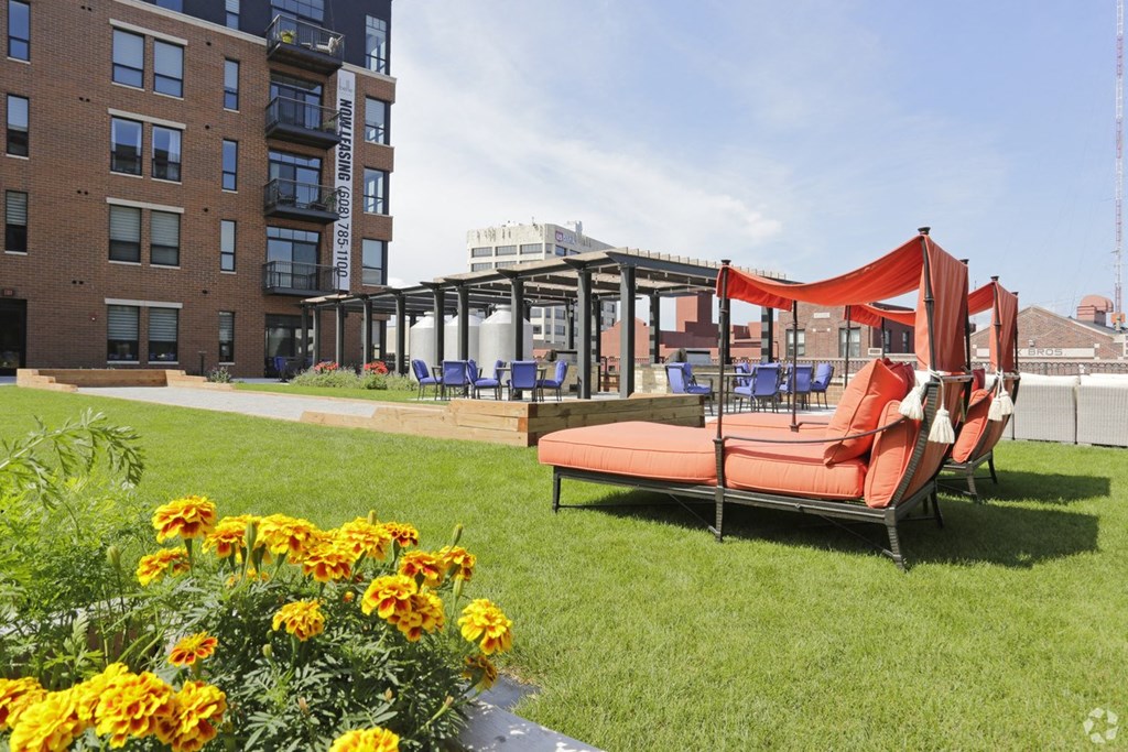 a lawn with lawn furniture and flowers in front of a building