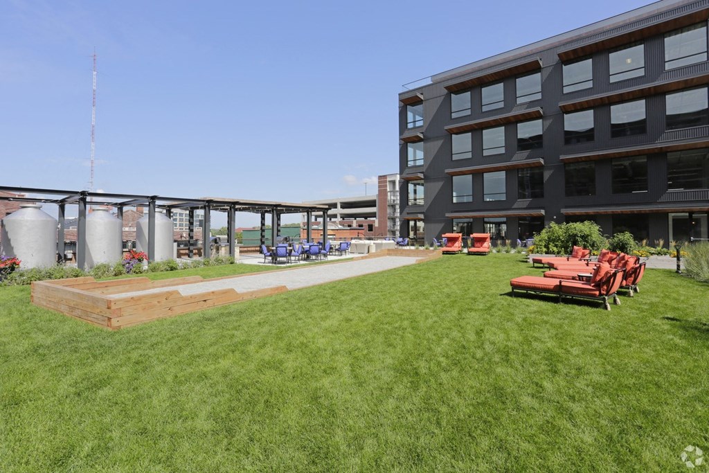 a grassy area with picnic tables and chairs in front of a building
