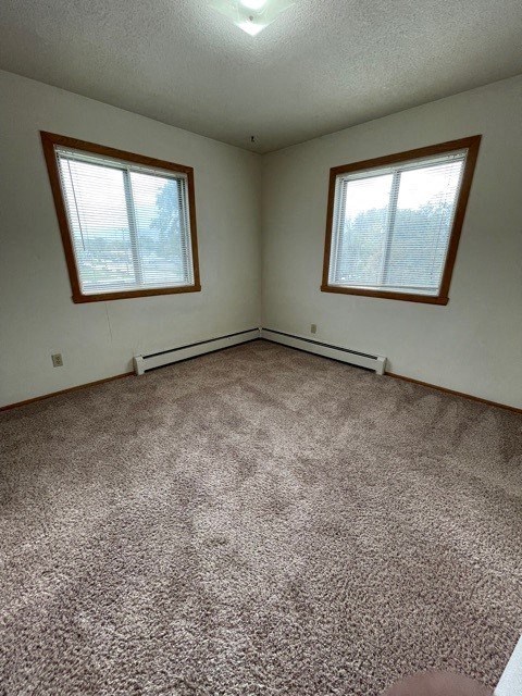 an empty room with two windows and a carpet