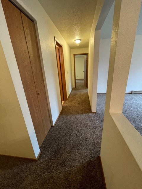 a long hallway with doors and a carpeted floor