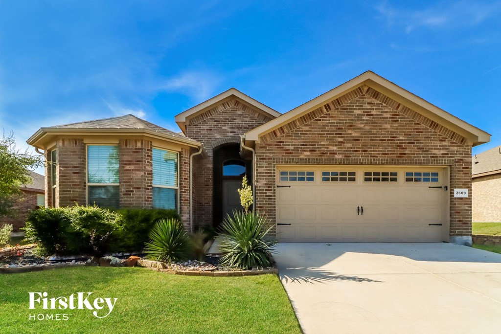 a brick house with a garage door and a lawn