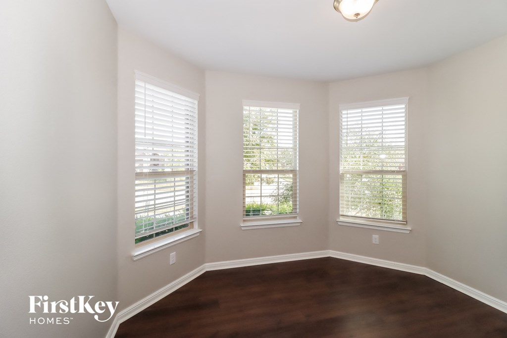 a living room with a hard wood floor and three windows