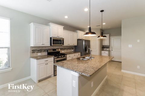 a large kitchen with white cabinets and granite counter tops