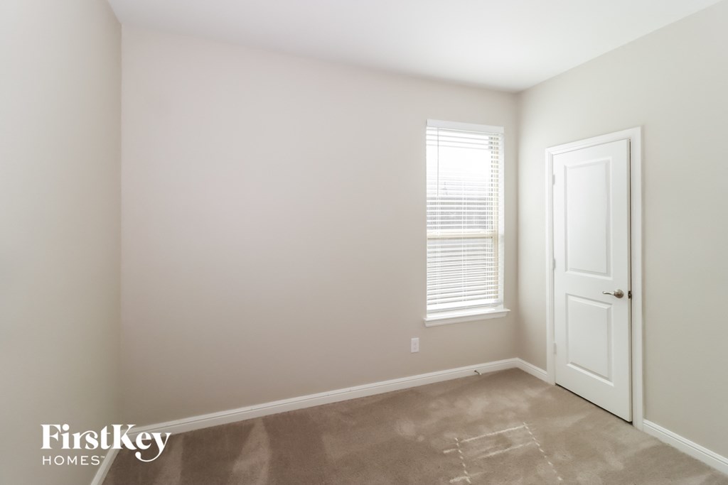 a bedroom with a white door and a window and a carpeted floor