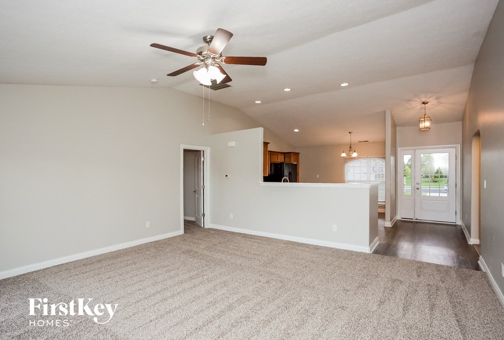 A spacious room with a ceiling fan and carpeted floor.