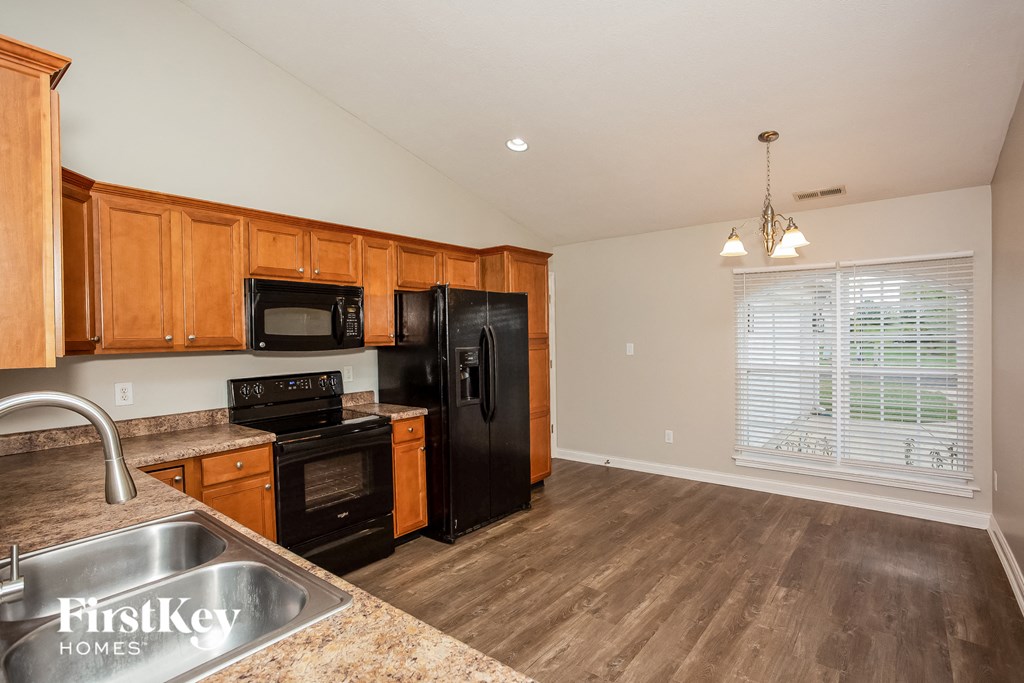A kitchen with wooden cabinets and a black refrigerator.