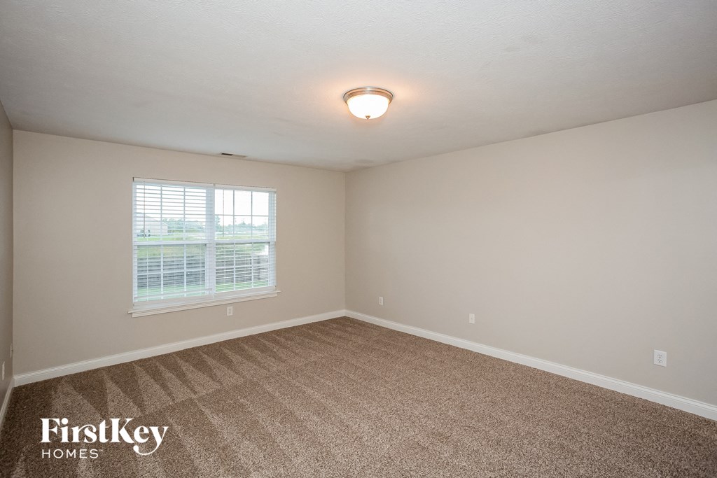 A room with a carpeted floor and a window with blinds.