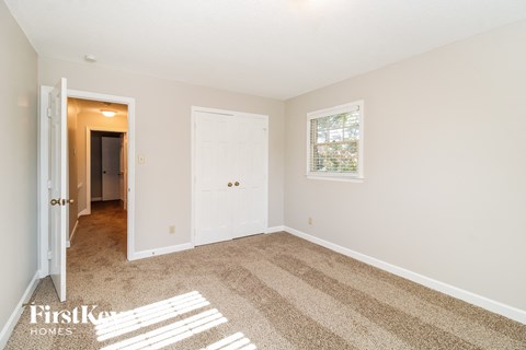 a spacious living room with carpet and a door to a hallway