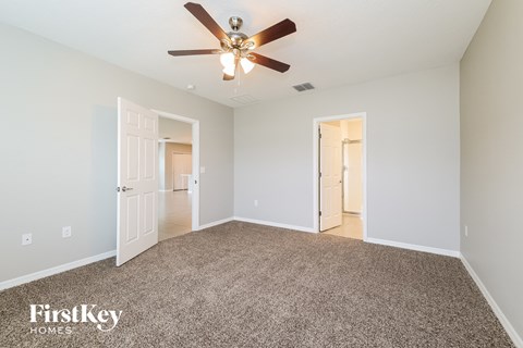 a spacious living room with carpet and a ceiling fan