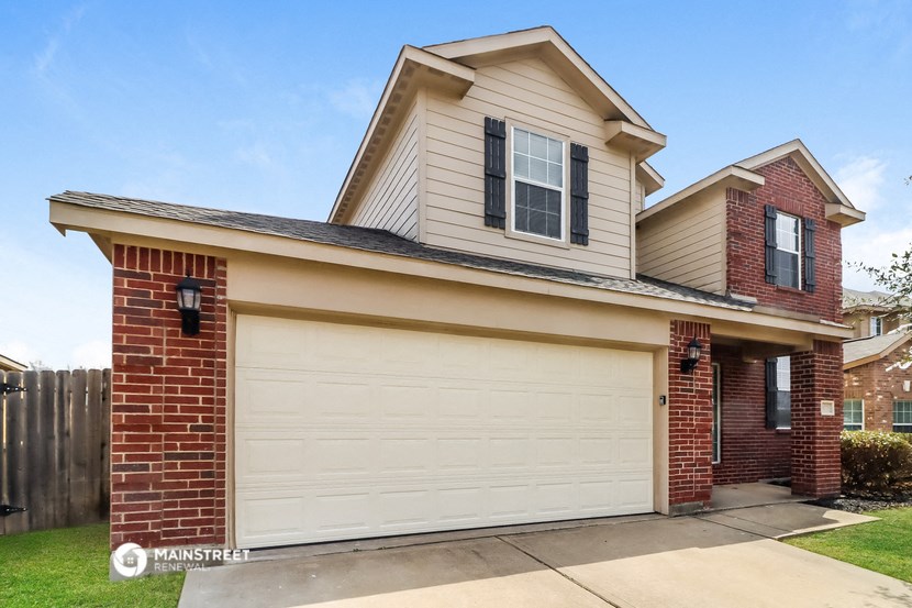 a home with a white garage door and a brick house