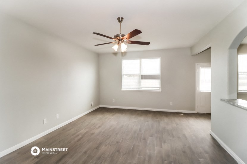 the spacious living room with ceiling fan and hardwood flooring