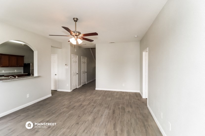 a spacious living room with white walls and a ceiling fan