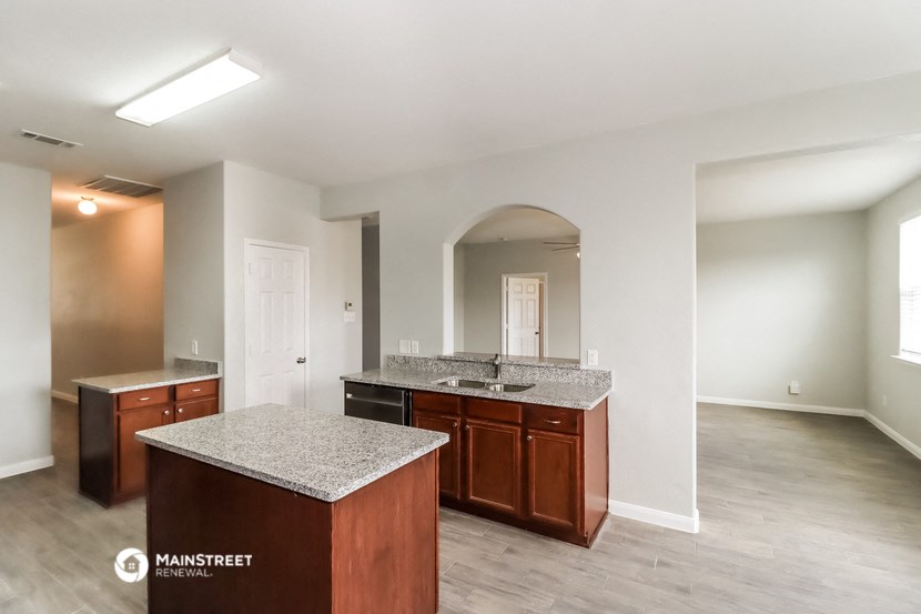 an empty kitchen with granite counter tops and wooden cabinets