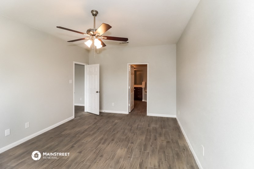 the spacious living room with ceiling fan and wood flooring