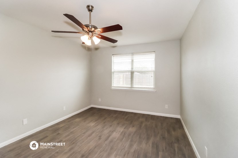the spacious living room with ceiling fan and wood flooring