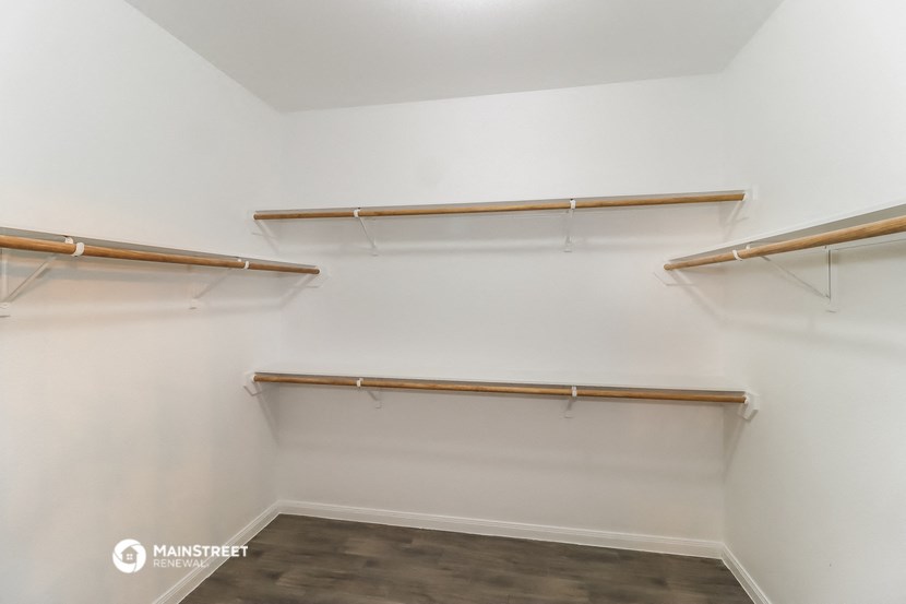 a walk in closet with empty shelves and a cement floor