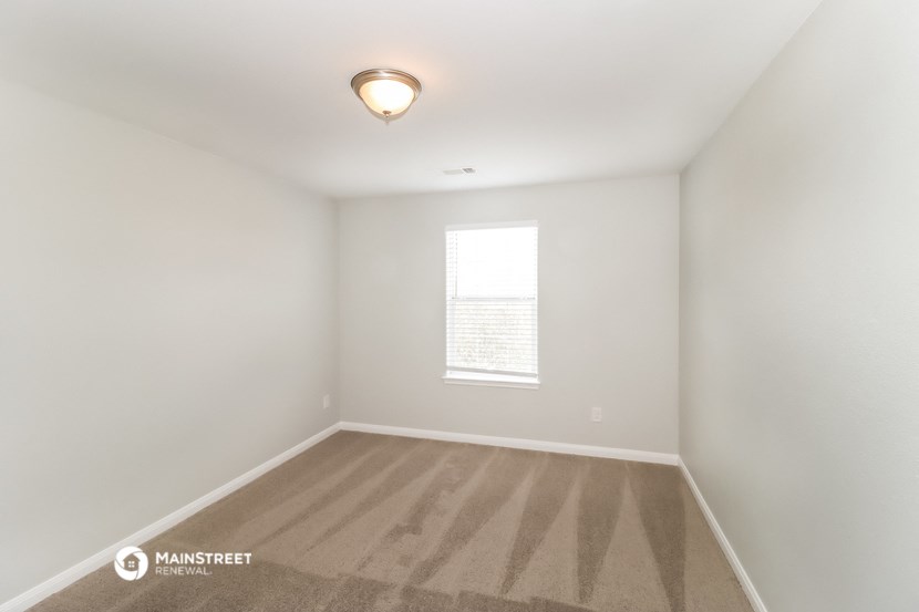 an empty room with a window and a lamp on the ceiling