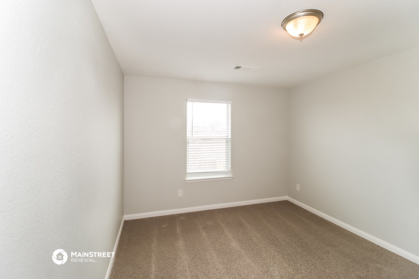 a spacious bedroom with carpet and a window