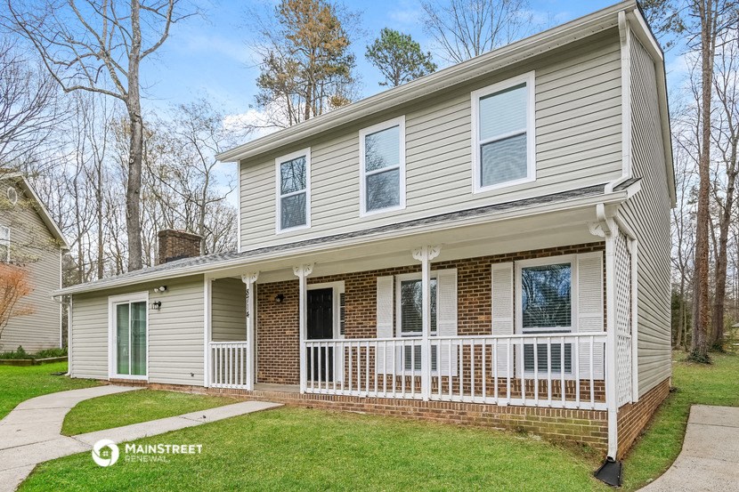 the front of a white house with a white porch and a lawn