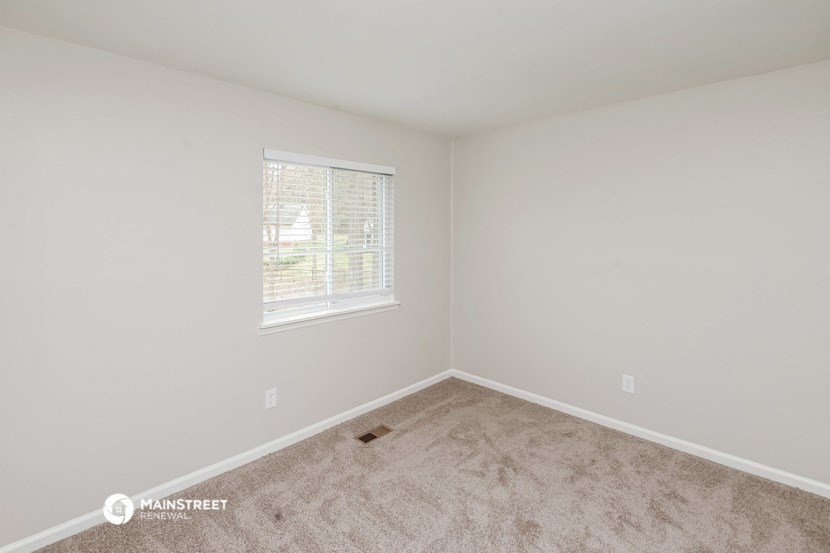 a spacious bedroom with carpet and a window