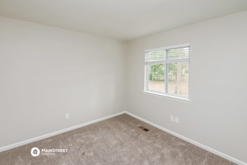 a bedroom with a window and a carpet