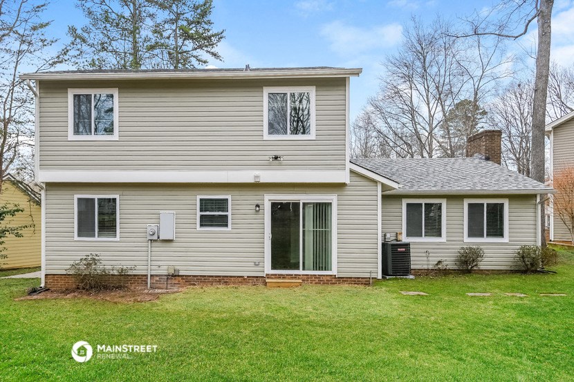 a white house with a green lawn and trees